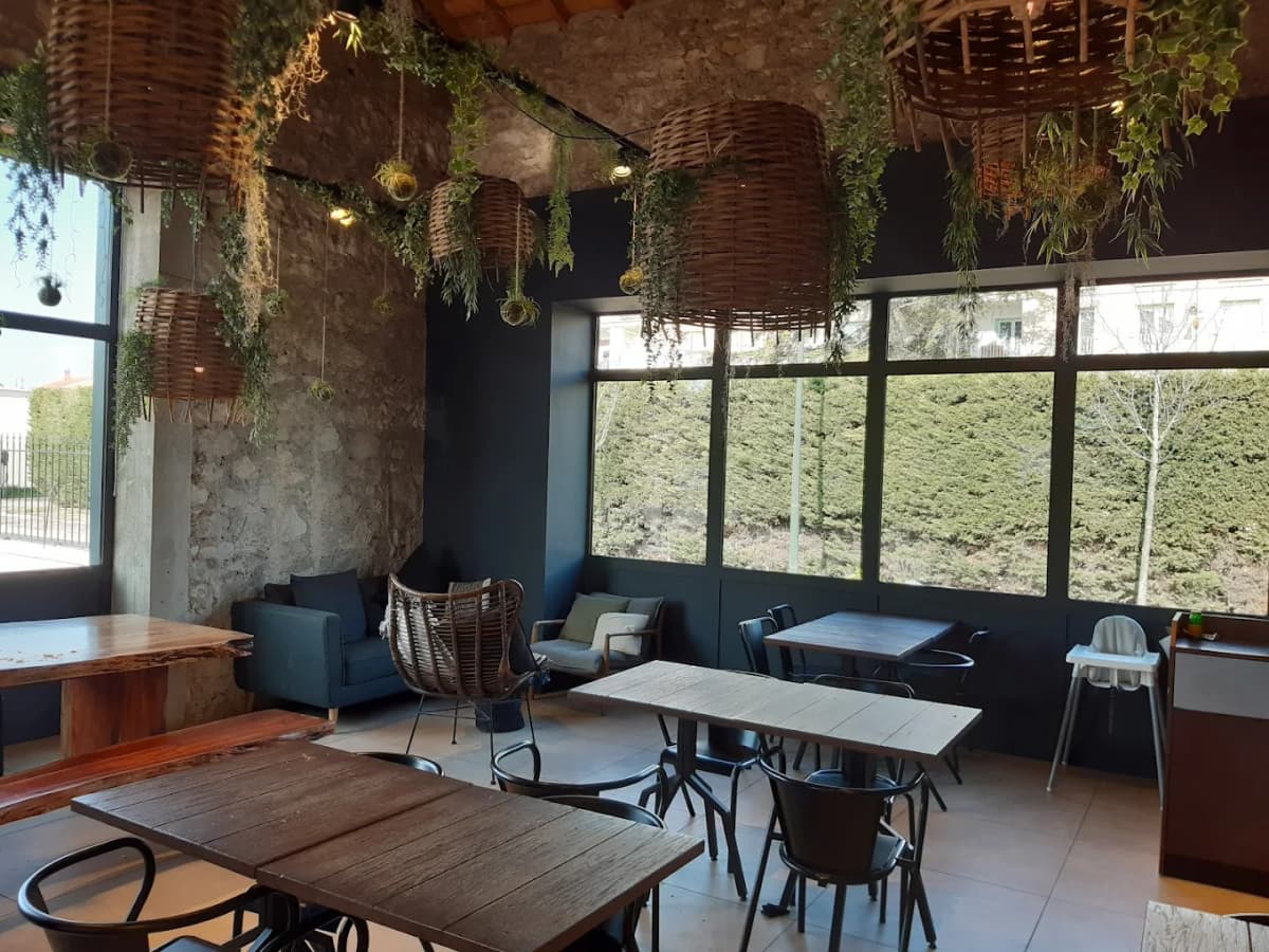 Intérieur chaleureux de la boulangerie Maison Leny avec son mobilier en fer forgé et ses tables en bois